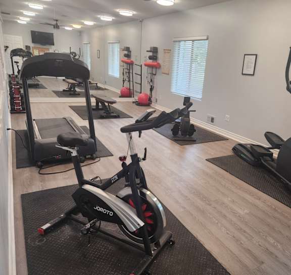 A gym with a variety of exercise equipment including a stationary bike, a rowing machine, and a treadmill.