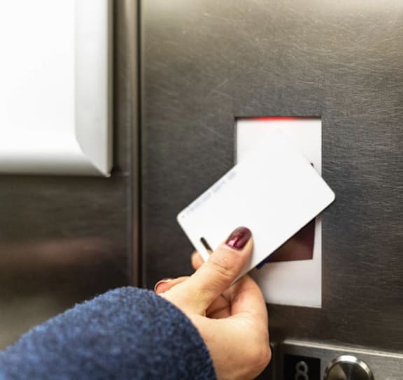 A person is inserting a white card into a slot on a metallic surface.
