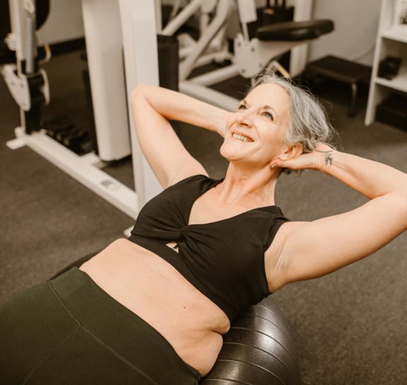 a woman doing a workout in a gym with her arms behind her head