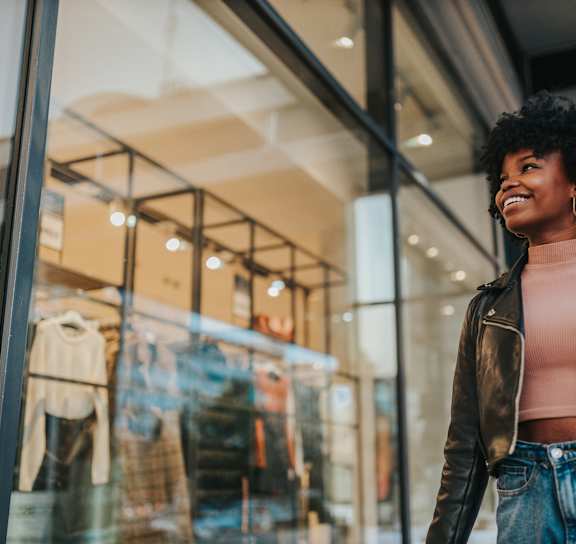 a woman smiling while standing in front of a store window at Orchard Lakes Apartments in Toledo, OH