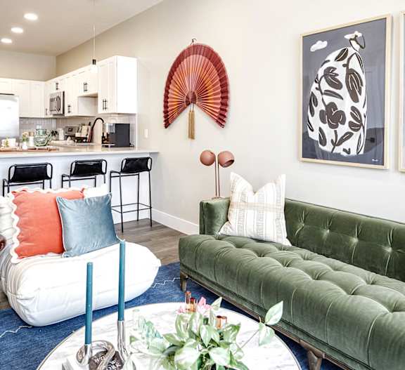 A living room with a green couch and a dining area in the background.