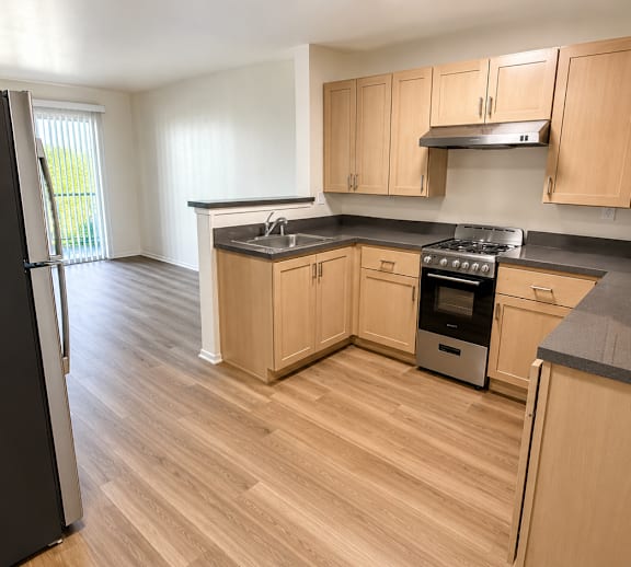 A kitchen with wooden cabinets and a black fridge.