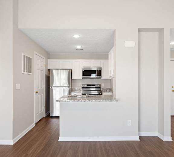 A kitchen with a white island and wooden floors.