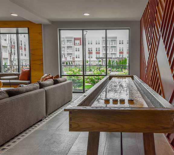 A shiny pool table in the middle of a room with a couch and a window.