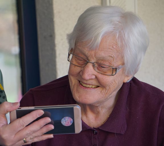 an older woman is looking at her cell phone while another woman wears a face mask