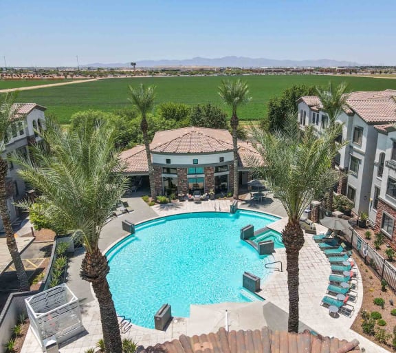 an aerial view of a resort style swimming pool with chaise lounge chairs and palm trees