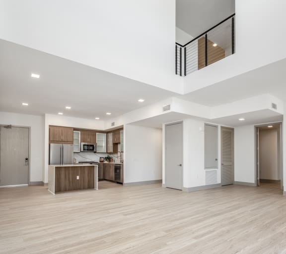 a renovated living room and kitchen with white walls and wood floors