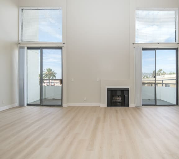 a kitchen and living room with white walls and wood flooring