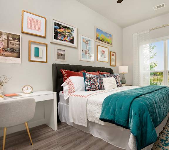 A bedroom with a large bed and a desk with a chair.