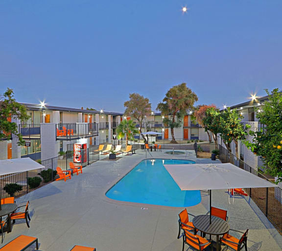 an outdoor pool with tables and chairs at an apartment complex at Allora Phoenix Apartments, Phoenix, Arizona