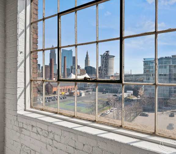 A view of a city skyline through a window with a brick wall on the left.