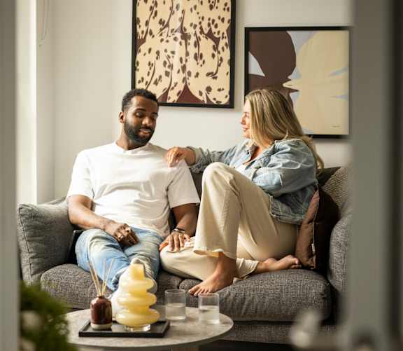 Man and a woman are lounging on a couch with a laptop and a book at Cenza, Manchester