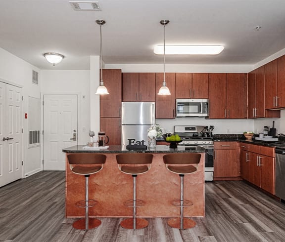 a kitchen with wooden cabinets and a island with three chairs