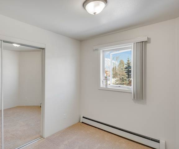 An empty carpeted bedroom with a window at La Maisonette Apartment Homes. 