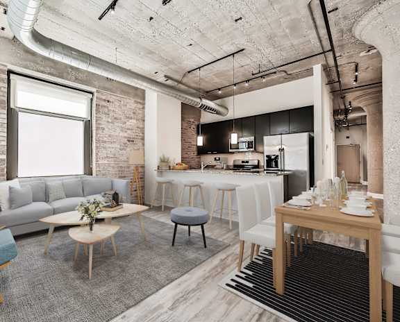 A modern living room with a grey sofa, wooden chairs, and a dining table set for two.