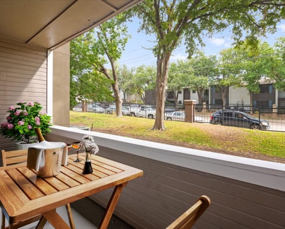 a balcony with a wooden table and two chairs and a large window with a view of a