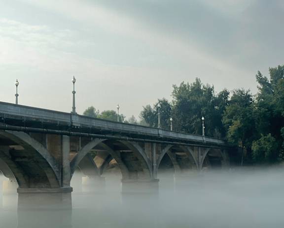 A bridge over a body of water with trees in the background.