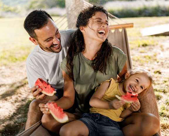 A family enjoying watermelon in a sunny outdoor setting.
