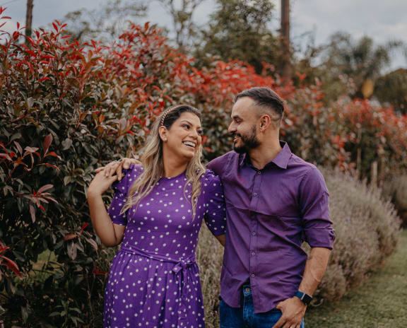 a man and woman standing in front of a row of flowers