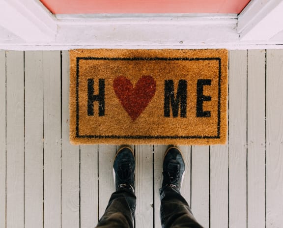 a man standing behind a home sign with a heart on it