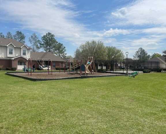 A playground with a slide and swings in a grassy area.