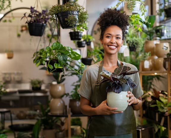 a woman holding a plant in a greenhouse