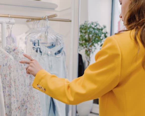 a woman looking at clothes on a rack