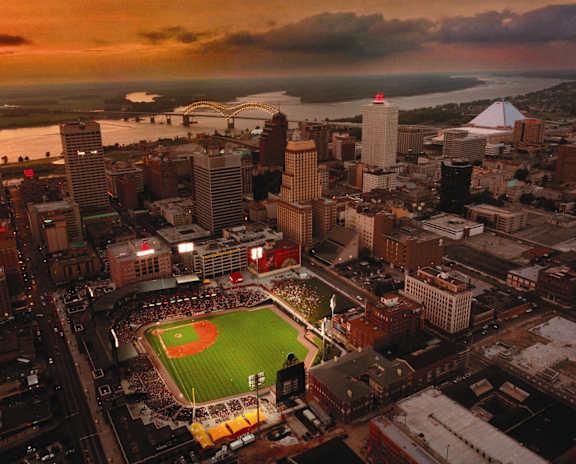 A baseball stadium is surrounded by buildings in a city.