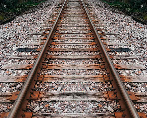 A railway track stretches into the distance surrounded by trees.