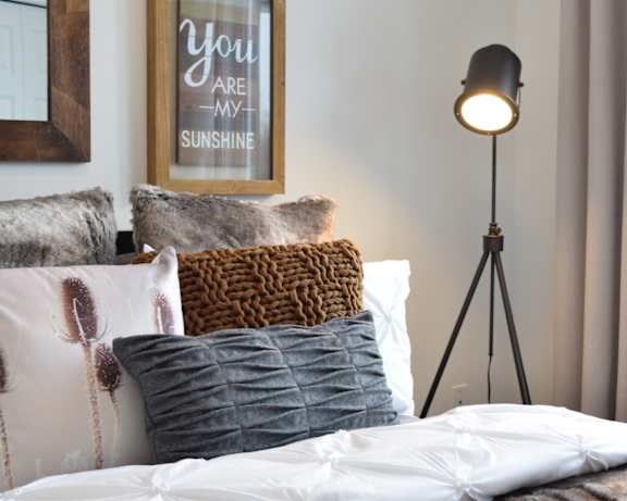A bed with pillows and a lamp in a room.