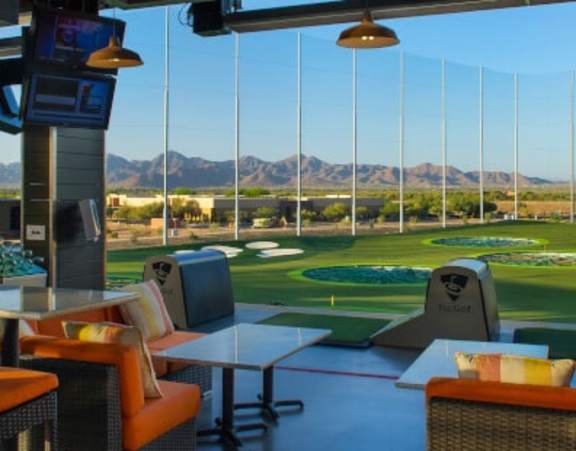 A view of a golf course from a room with a table and chairs.