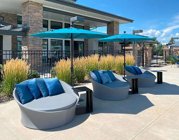 A patio with two grey couches and blue pillows.