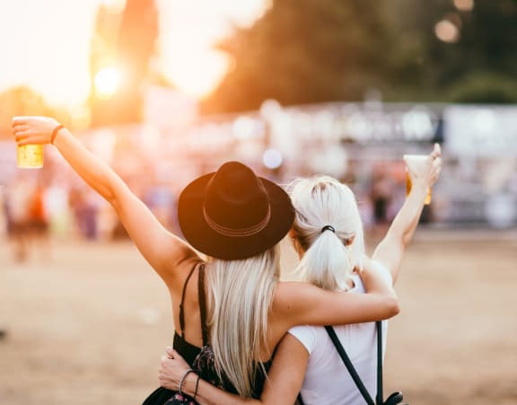 two women holding their hands up in the air at an outdoor event