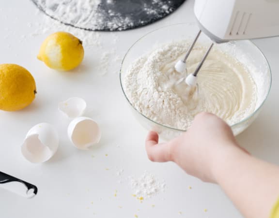 a person mixing dough in a bowl with a hand mixer