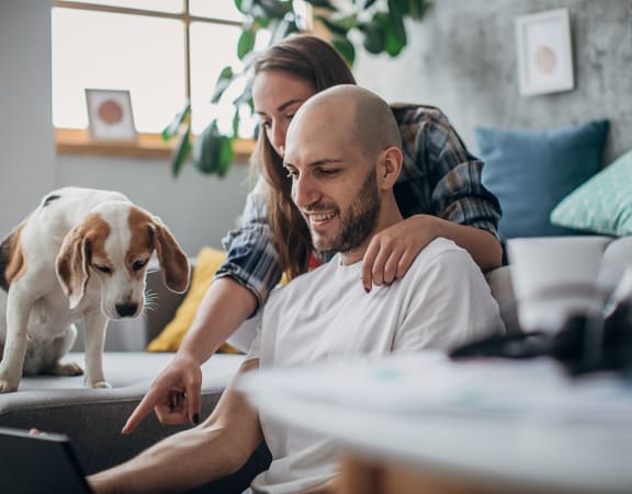 a man and woman sit on a couch with a dog and look at a laptop at Topaz Apartments, Los Angeles, CA, 90013