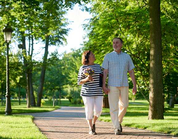 A man and a woman walking in a park.