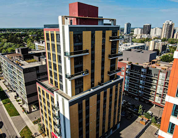 A tall building with a red top stands out against a cityscape.