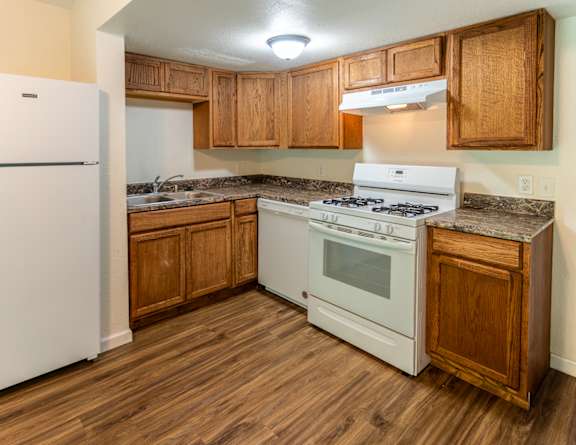 A kitchen with a white fridge, white stove and wooden cabinets. at Arbor Pointe Townhomes Apartments, Battle Creek, MI, 49037