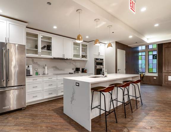 A kitchen with a refrigerator, bar stools, and a window at Park Heights by the Lake Apartments, Illinois, 60649.
