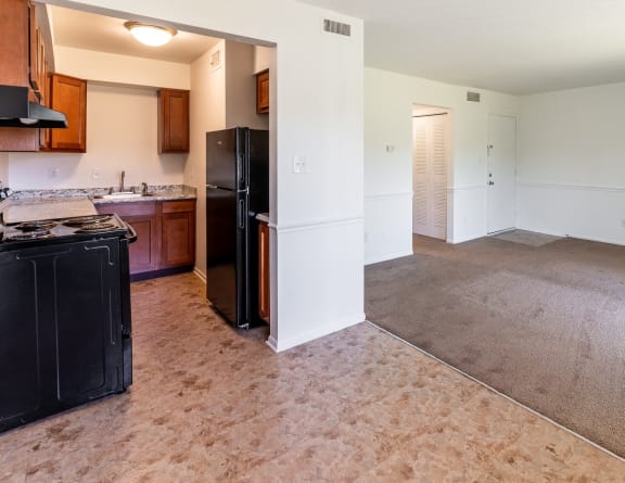 an empty kitchen and living room with a black refrigerator