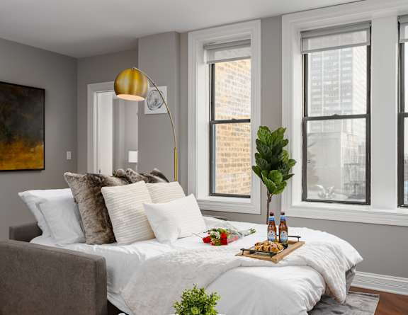 a living room with a bed and a lamp and windows