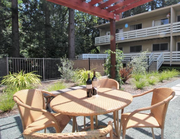 a patio with a table and chairs and a bottle of wine