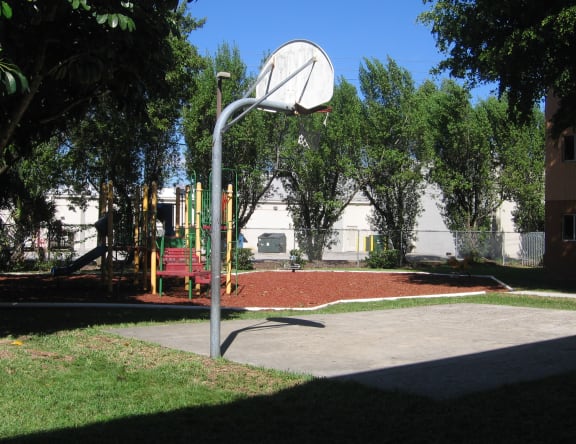 a basketball hoop in a park with a playground in the background