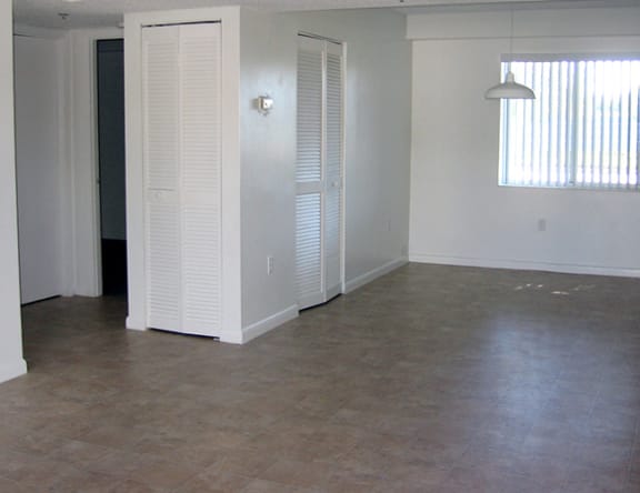 an empty living room with a window and a closet