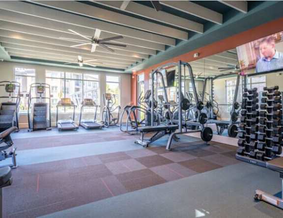 A gym with a variety of equipment including treadmills, weights, and exercise machines.