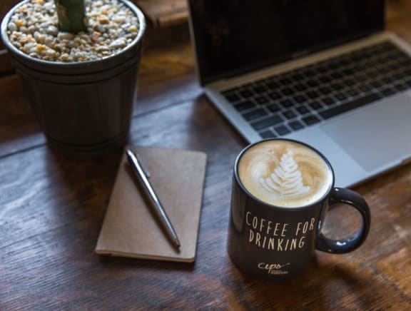Cup of coffee next to a laptop