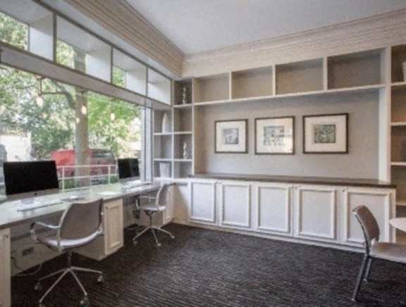 A room with a desk, chairs, and pictures on the wall.