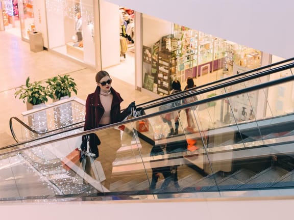 a woman riding an escalator in a shopping mall