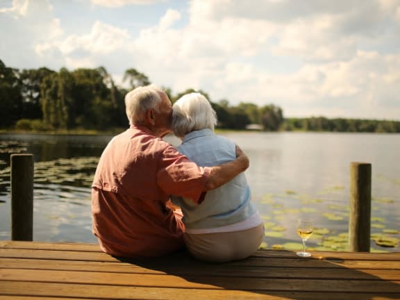 an older couple kissing on a dock overlooking a lake at Windsor Crossing Senior, Suitland, MD 20746