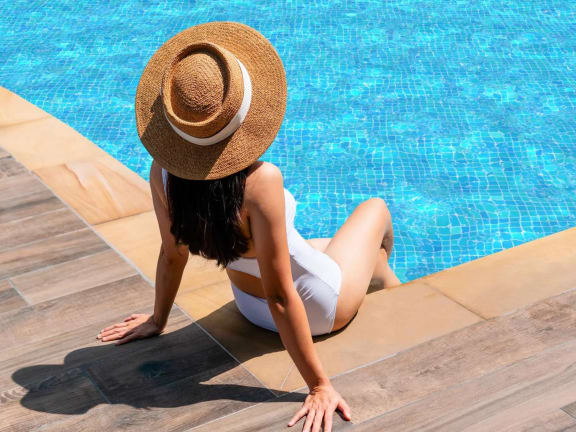 the back of a woman sitting by the pool wearing a hat at Tranquility Grove, Houston, Texas